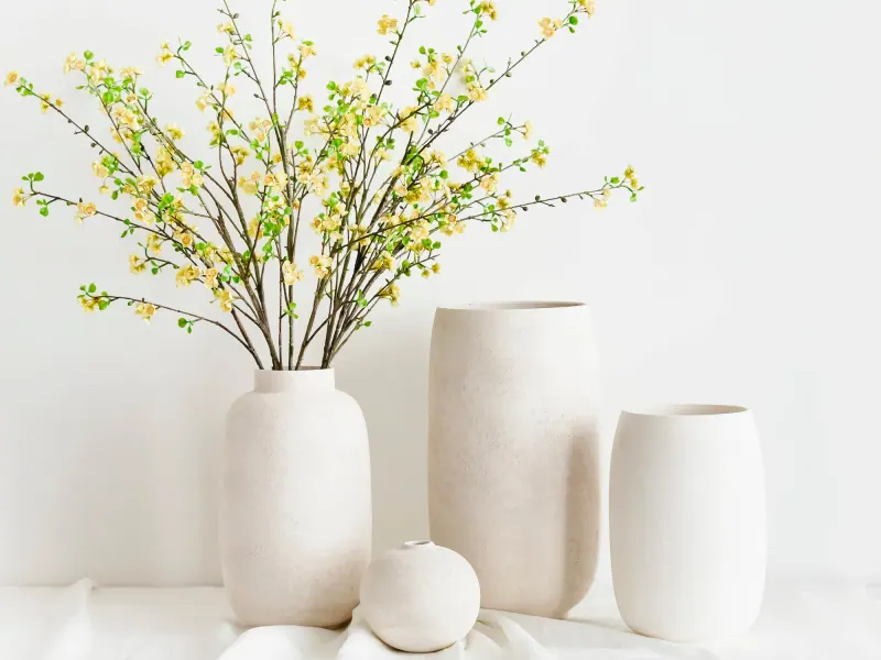 Cremeweiße Vasen aus Steinzeug von S|P Collection mit blühenden Zweigen vor einer hellen Wand